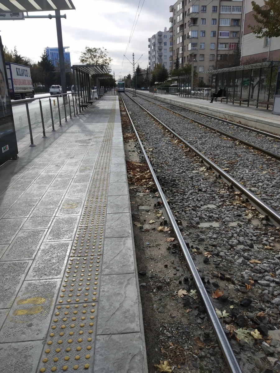 Konya’da karşılıklı tramvay peronları, raylar ve peron boyunca uzanan sarı hissedilebilir yüzey.