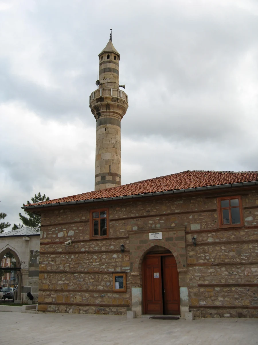 Muallimhane Camii’nin yatay ahşap hatıllı taş cephesi, kemerli giriş kapısı ve minaresi.