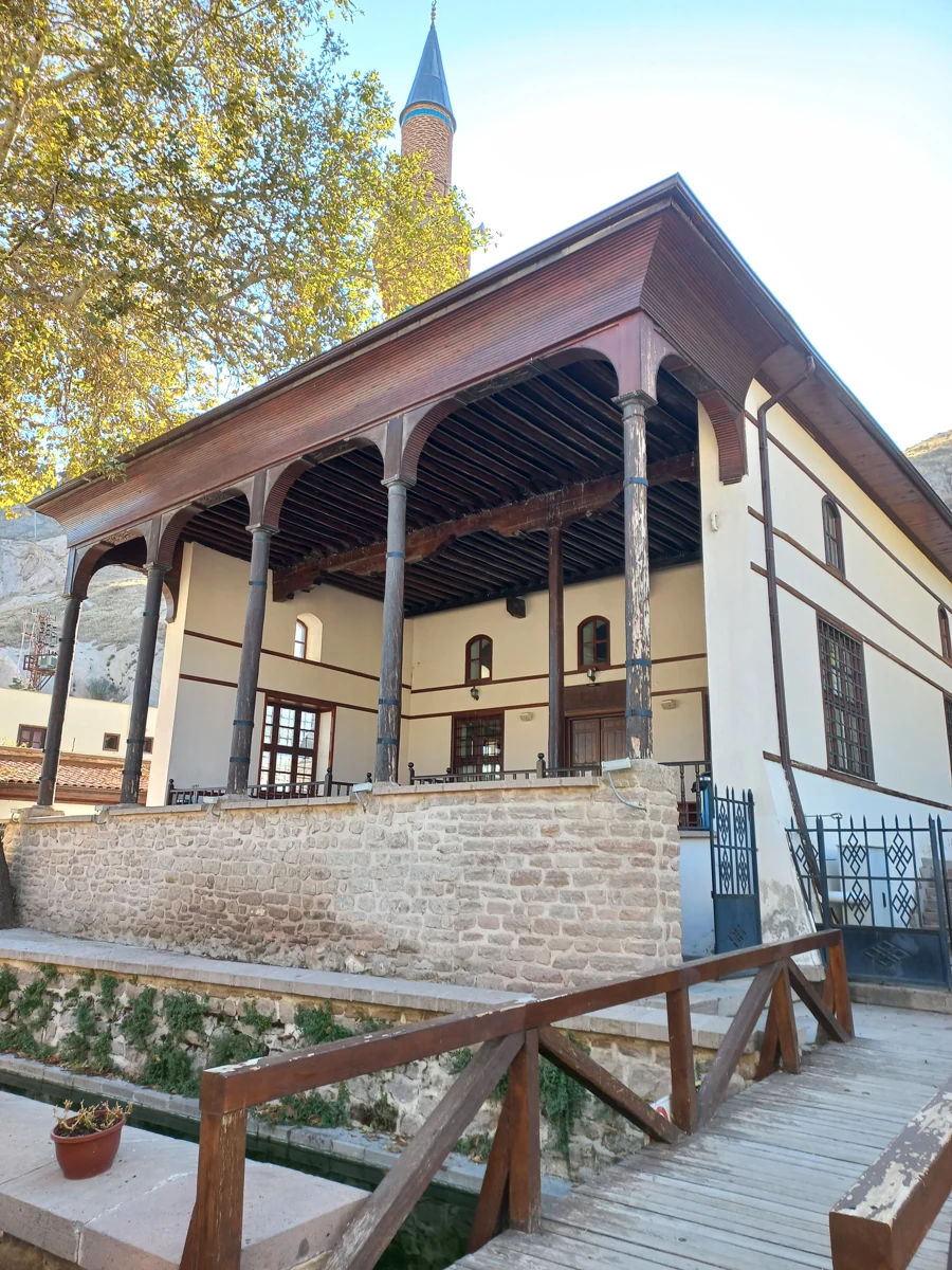 Sille Çay Camii’nin ahşap sütunlu revakı, minaresi ve taş duvarı; önünde su kanalını geçen ahşap köprü.