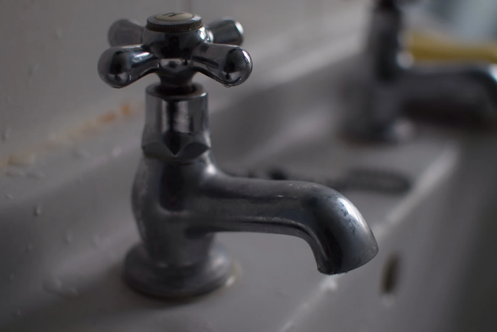 Bulanık arka plan önünde koyu renkli lavabo musluğu